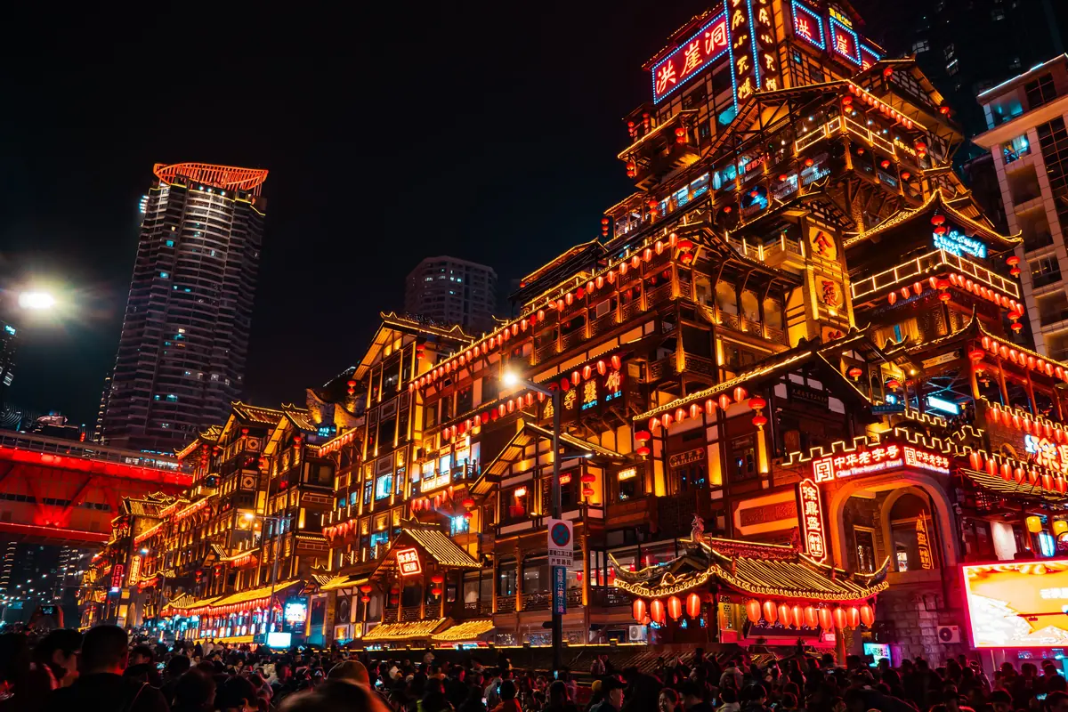 Hongya Cave lit red and gold beneath a bridge in Chongqing at night, shown for its stilted look. It is a different place from the theatre.
